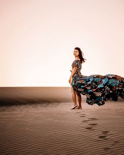 Full length portrait of woman standing at desert