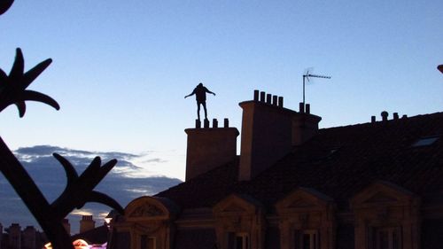 Low angle view of silhouette houses against sky