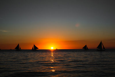 Silhouette sailboat sailing on sea against sky during sunset