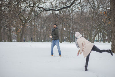 Happy couple playing on snow covered land during winter