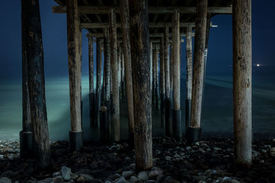 Columns of pier on beach at dusk