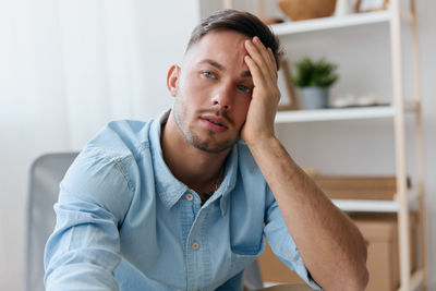 Young man with head in hand at home