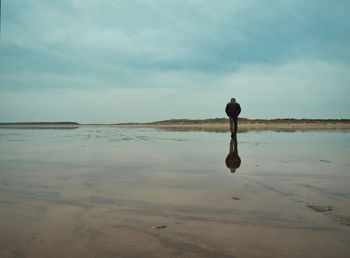 Man standing on beach against sky