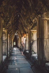 Side view of woman standing in old historic corridor