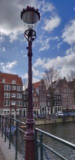 Street light in city against cloudy sky