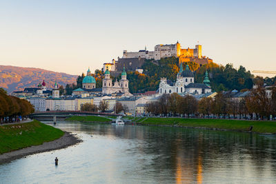 Buildings by river against clear sky