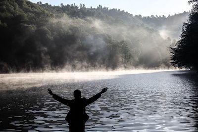 Rear view of woman overlooking calm lake