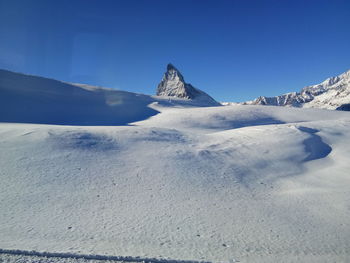 Scenic view of snowcapped mountains against clear blue sky