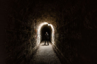 Rear view of man walking in tunnel