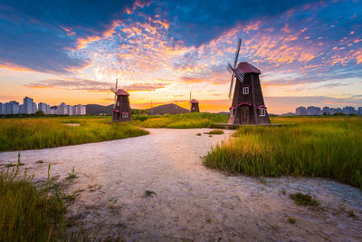 Traditional windmill on field against sky during sunset