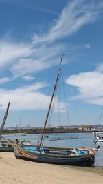 Sailboats moored on beach against sky