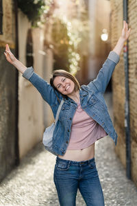 Portrait of young woman with arms outstretched standing outdoors