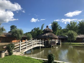Gazebo by lake and building against sky