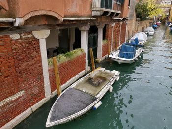 Boats moored in canal amidst buildings in city