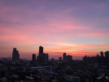 Buildings in city against romantic sky at sunset