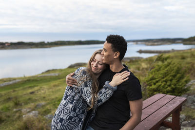 Smiling couple hugging at lake