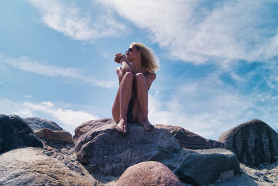 Woman standing on rock against sky