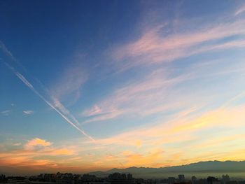 Low angle view of vapor trail in sky during sunset