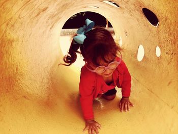 Cute girl crawling in play equipment at playground