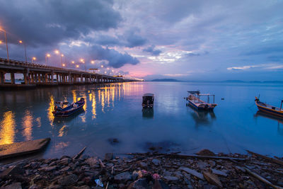 Boats moored on sea against sky during sunset