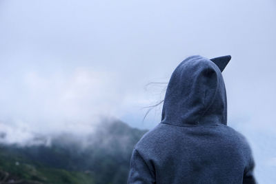 Rear view of woman against sky during winter