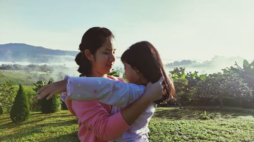 Rear view of mother and daughter standing against sky