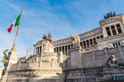 Low angle view of statues against sky and vittoriano, altare della patria 