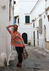 Portrait of woman standing in alley amidst buildings