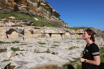 Side view of young woman standing on land against clear blue sky