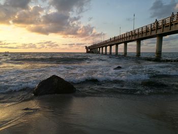 Bridge over sea against sky during sunset