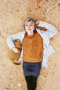 Directly above of young woman lying at beach