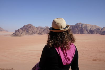 Rear view of woman standing in desert against sky