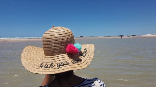 Rear view of hat on beach against clear sky