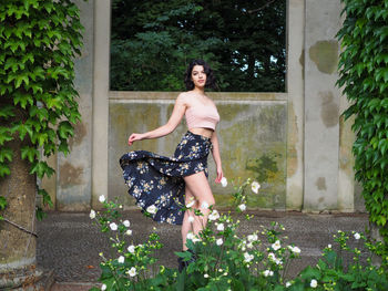 Portrait of smiling young woman standing against plants