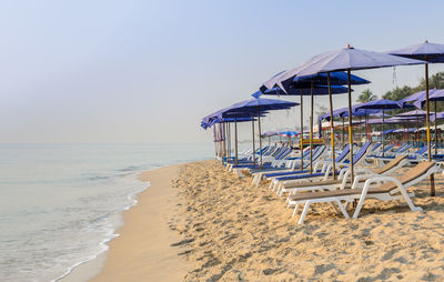 Deck chairs on beach against clear sky