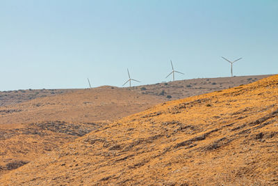 Wind turbines on land against clear sky