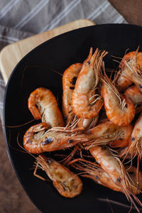 Close-up of grilled prawns in bowl on serving board