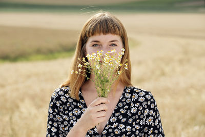 Portrait of young woman with bunch of chamomile flower