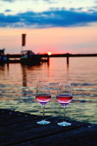 Close-up of wine glass by sea against sunset