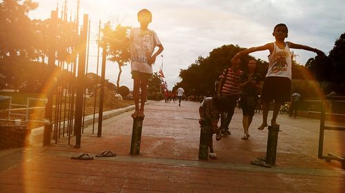 Group of people jumping on beach against sky during sunset