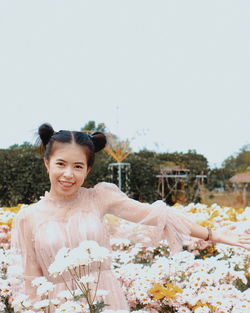 Portrait of smiling young woman against plants and trees against clear sky