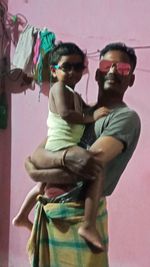 Young man wearing sunglasses standing against wall