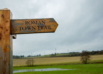 Road sign on field against sky