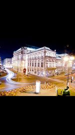 Light trails on road against buildings at night