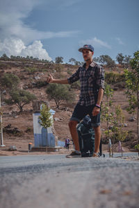 Full length of young man looking away against trees