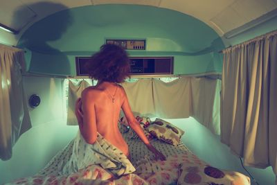 Rear view of woman standing in bed