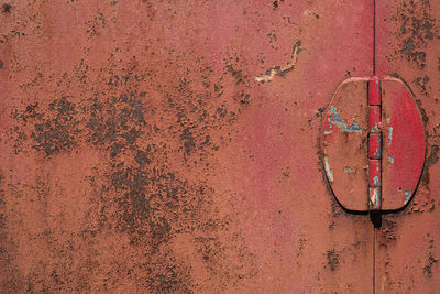 Old red iron door, rusted steel surface texture, rough peeling paint with door hinge