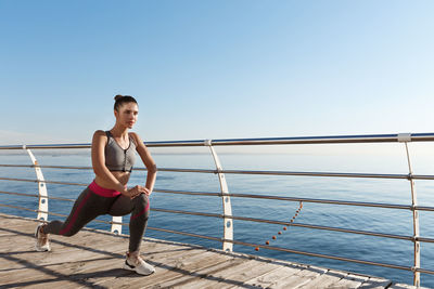 Full length of woman standing by railing against clear sky