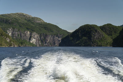 Scenic view of sea by mountains against clear sky