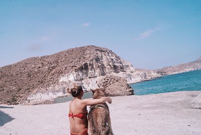 Rear view of shirtless man on beach against sky